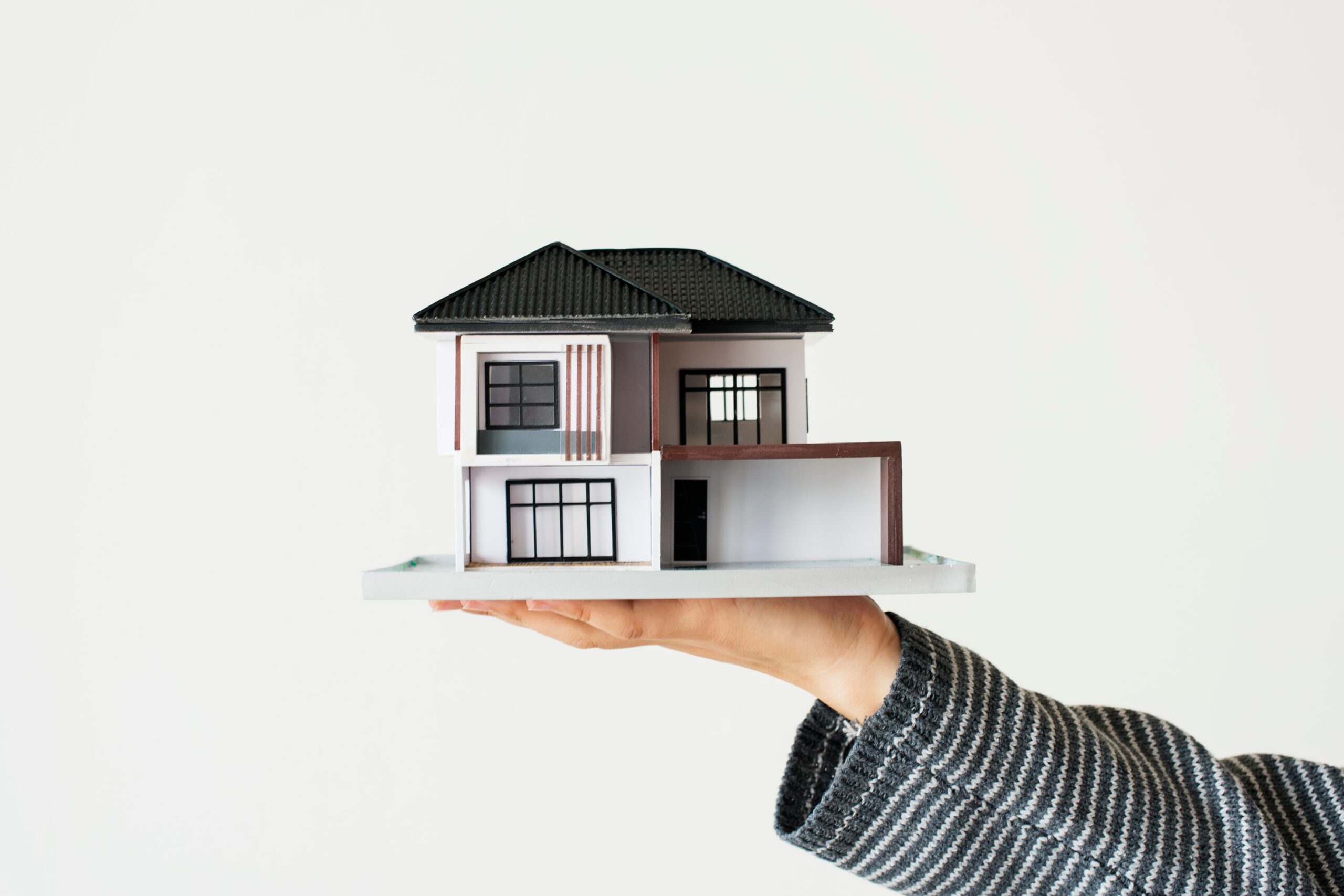 Concepto de préstamo de vivienda con casa en miniatura sobre fondo blanco