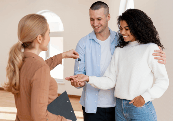 Agente inmobiliario entregando llaves a una pareja en su nuevo hogar